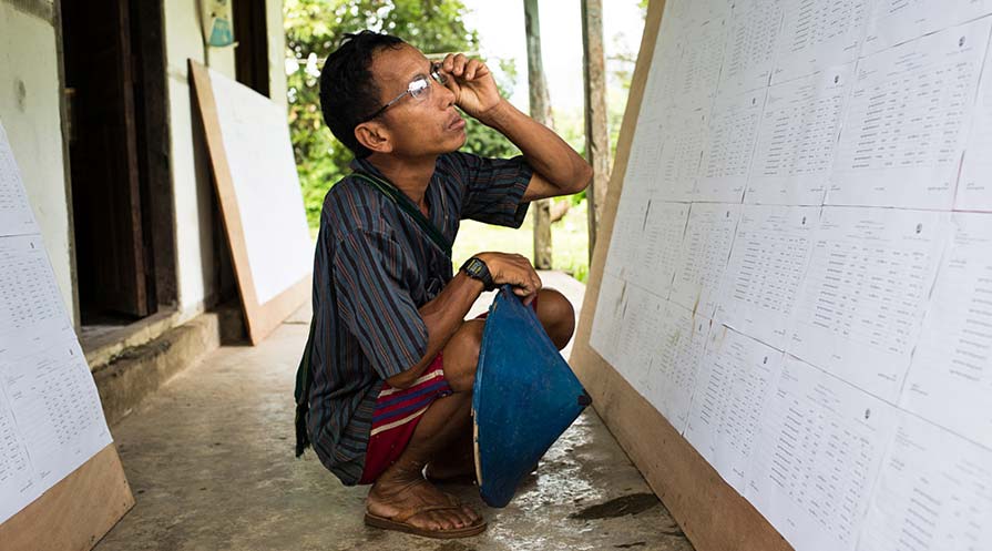 Photo of a voter checking for his name on a voter list display.