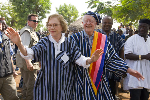 Jimmy and Rosalynn Carter watch as a health worker dresses a child's Guinea worm wound.